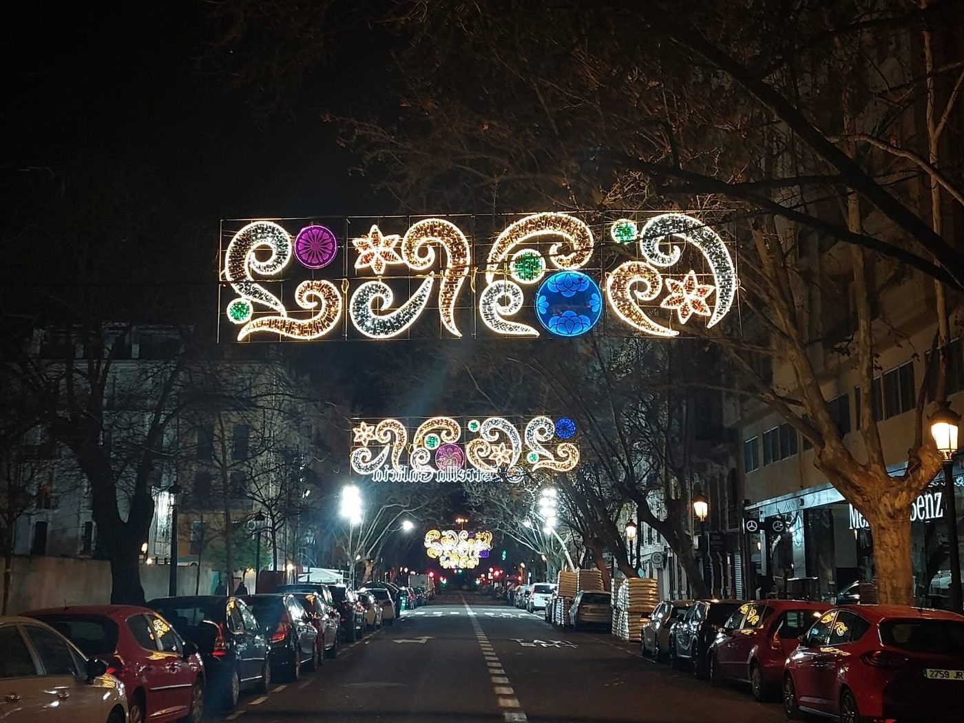 Arabescos luminosos sobre una calle arbolada
