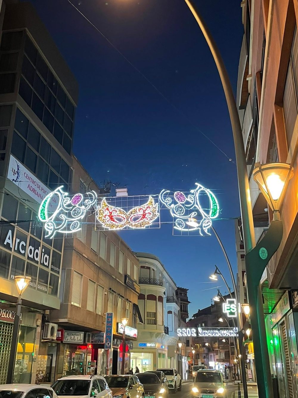 Máscaras luminosas de Carnaval colgadas sobre la calle al anochecer